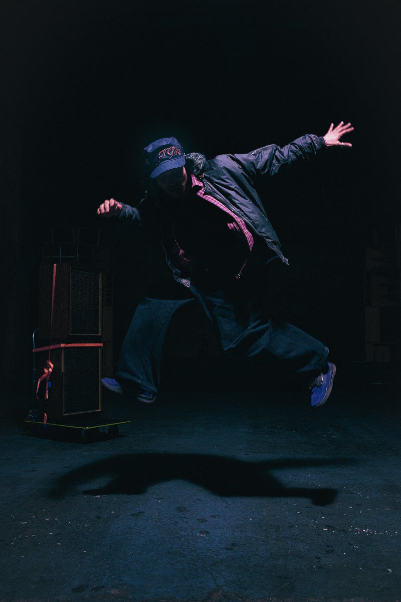 A dancer in the ANTIFRAGILE Miliary Fur Hat suspended in the air as they dance.
