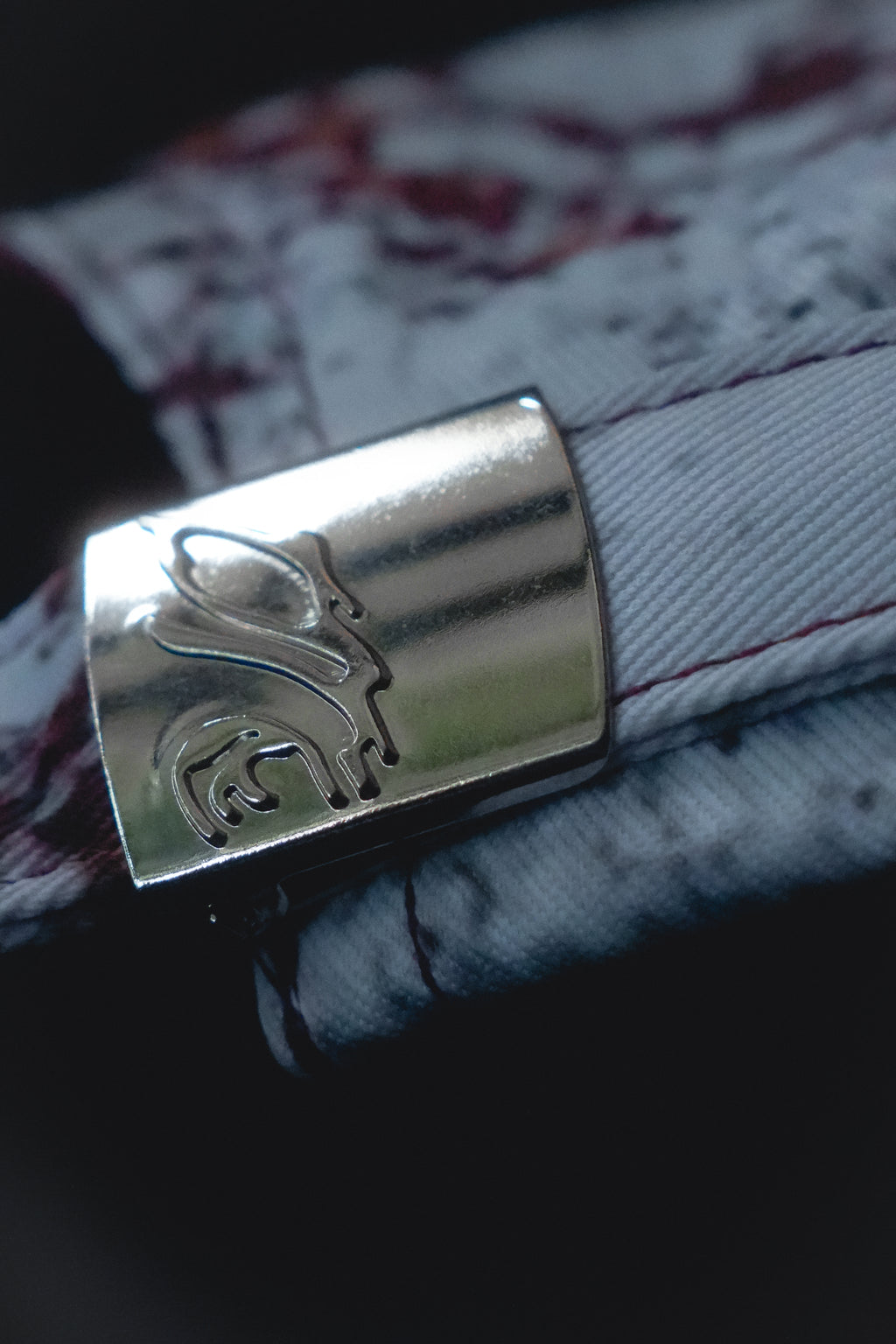 Close-up of a silver buckle with a embossed logo.