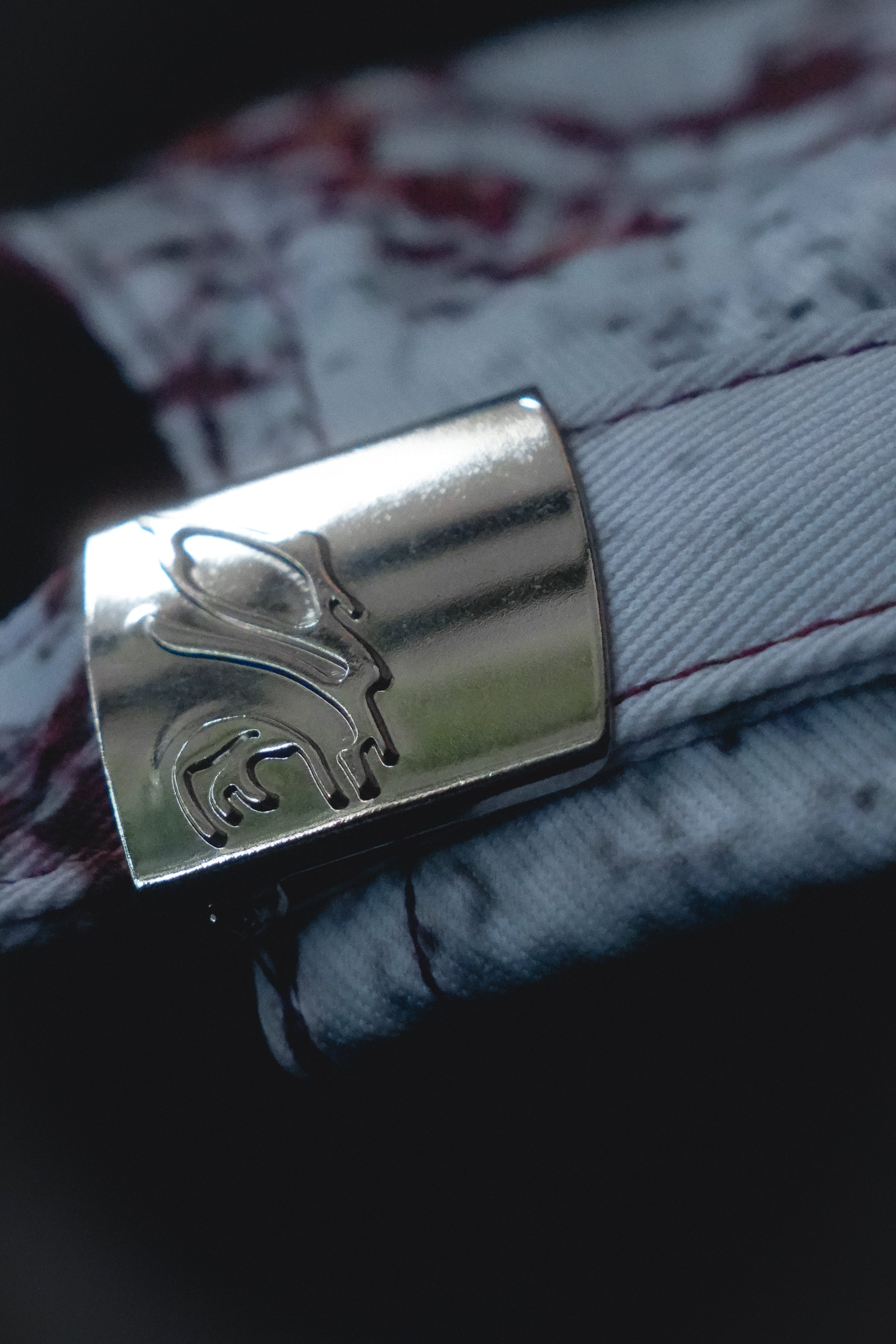 Close-up of a silver buckle with a embossed logo.