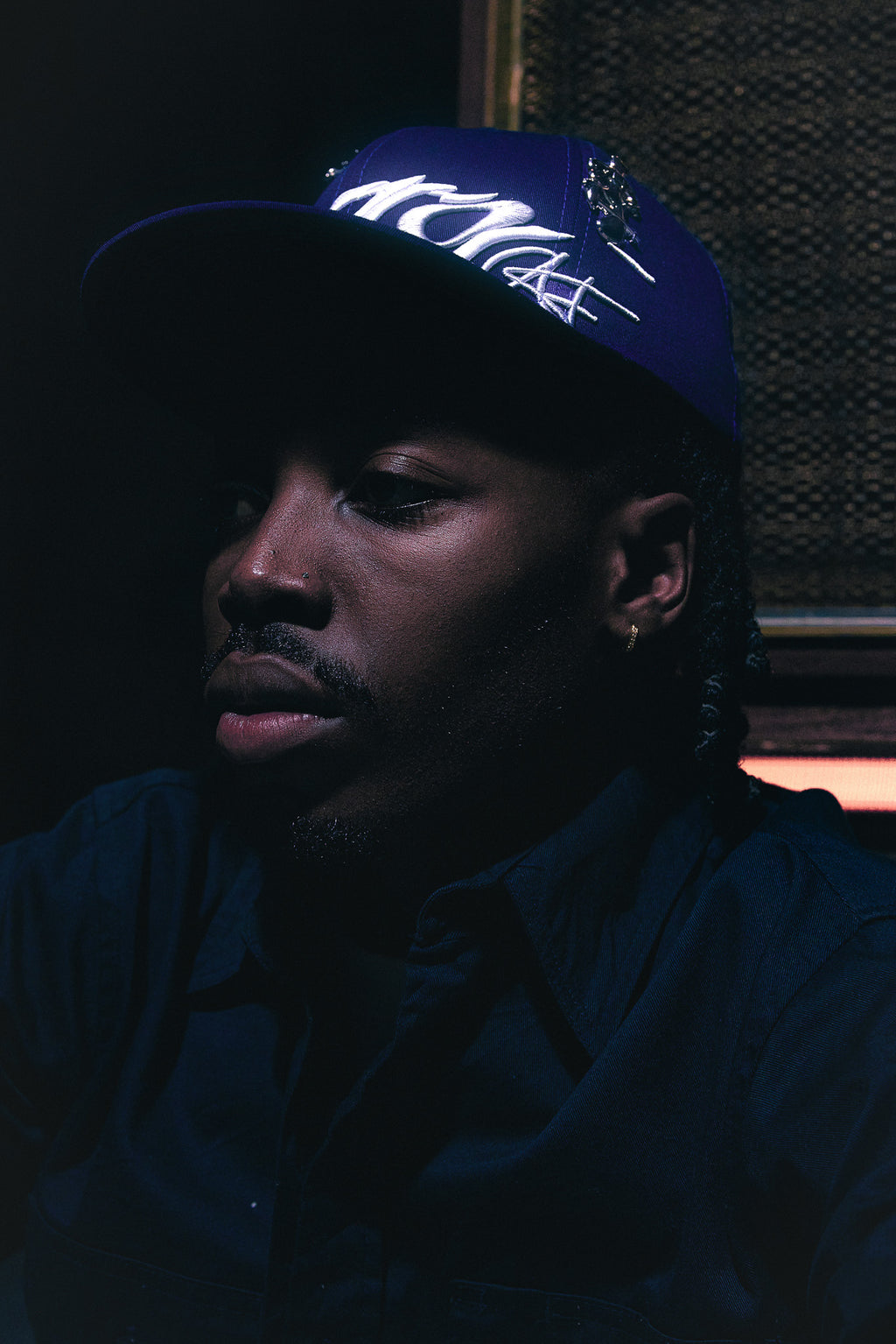 Person wearing the ANTIFRAGILE Fitted Navy Blue Hat showcasing the 3D puff embroidery.