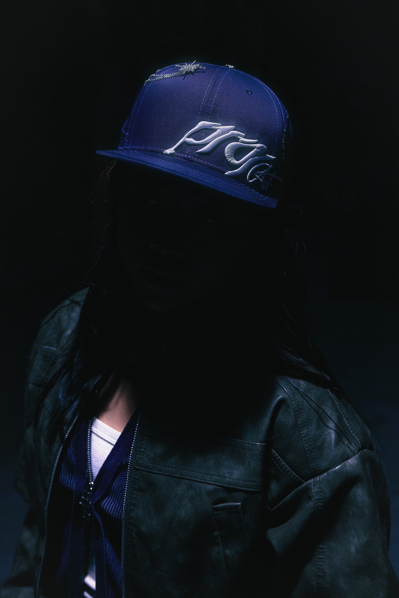 A creative seen wearing the ANTIFRAGILE Navy Blue Fitted Cap showcasing the 3D puff print embroidery.