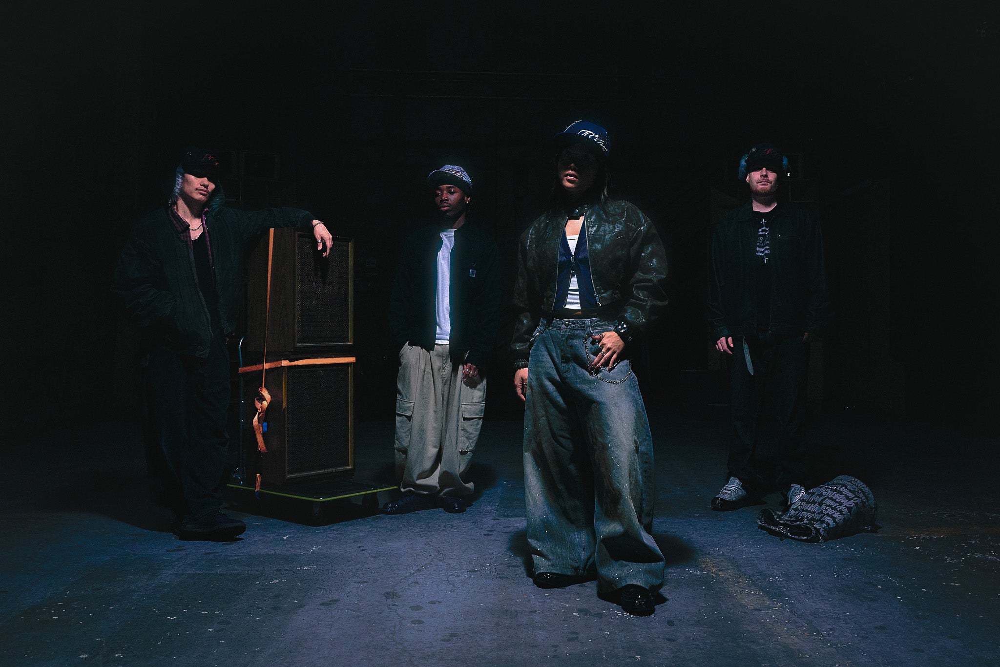 Four creatives in dark clothing, each wearing their own Project Antifragile Hat, a codesigned creative identifier customised with their creative roles.